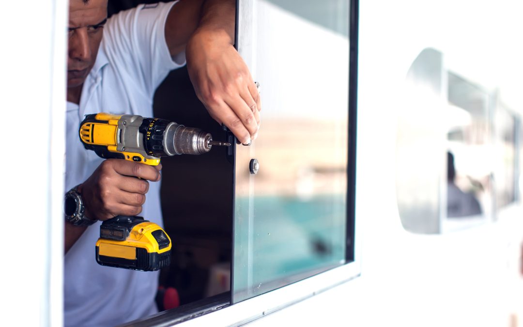 A man works on a window with an electric screwdriver